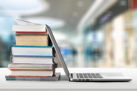 Laptop open and leaning against a pile of books