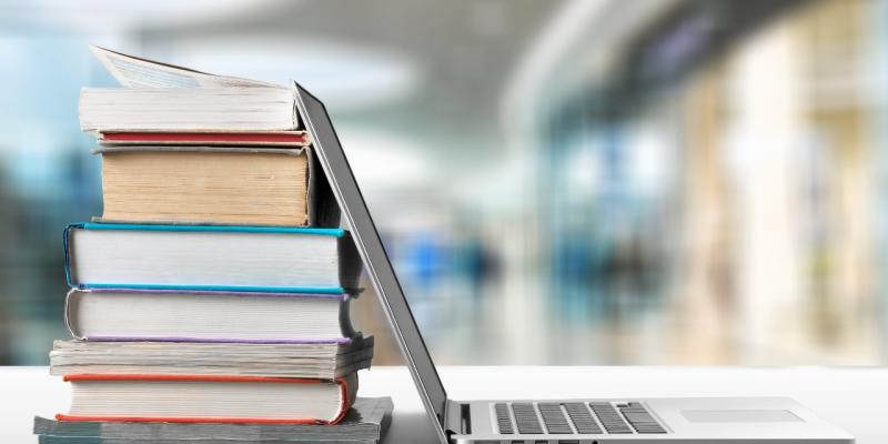 Laptop open and leaning against a pile of books